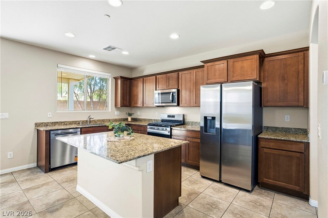 2221 Mundare Drive, Henderson, NV 89002 Rich wood cabinetry and polished granite countertops anchor this kitchen designed with a central island.