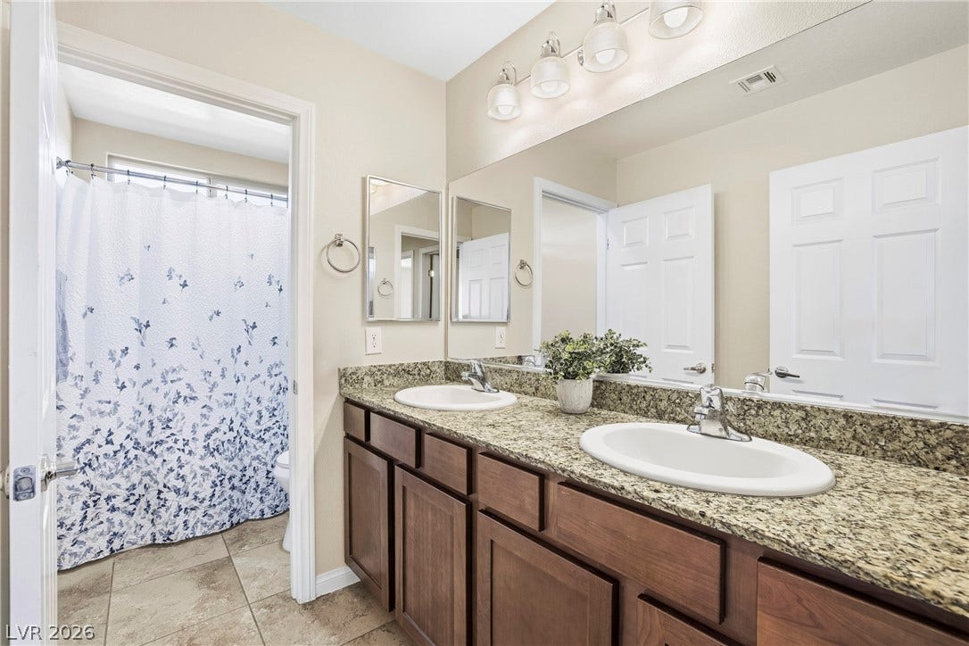 2221 Mundare Drive, Henderson, NV 89002 A spacious double vanity features granite countertops and tile flooring.