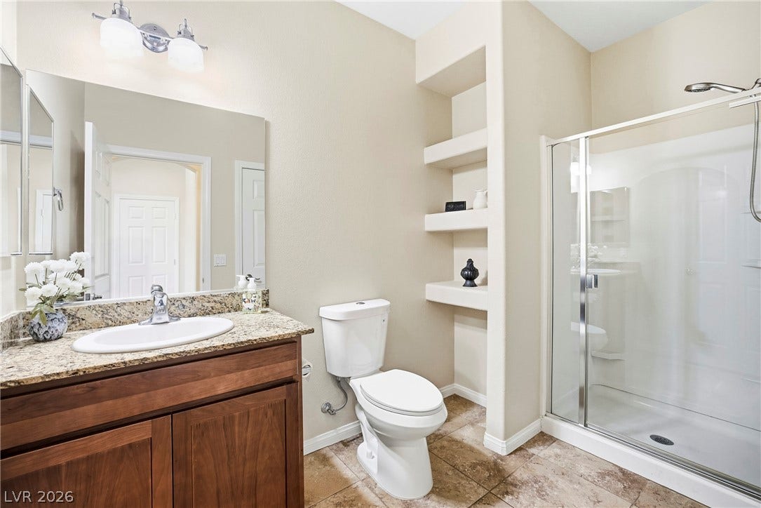 2221 Mundare Drive, Henderson, NV 89002 Rich wood cabinetry paired with granite countertops anchors this modern, functional bathroom design.
