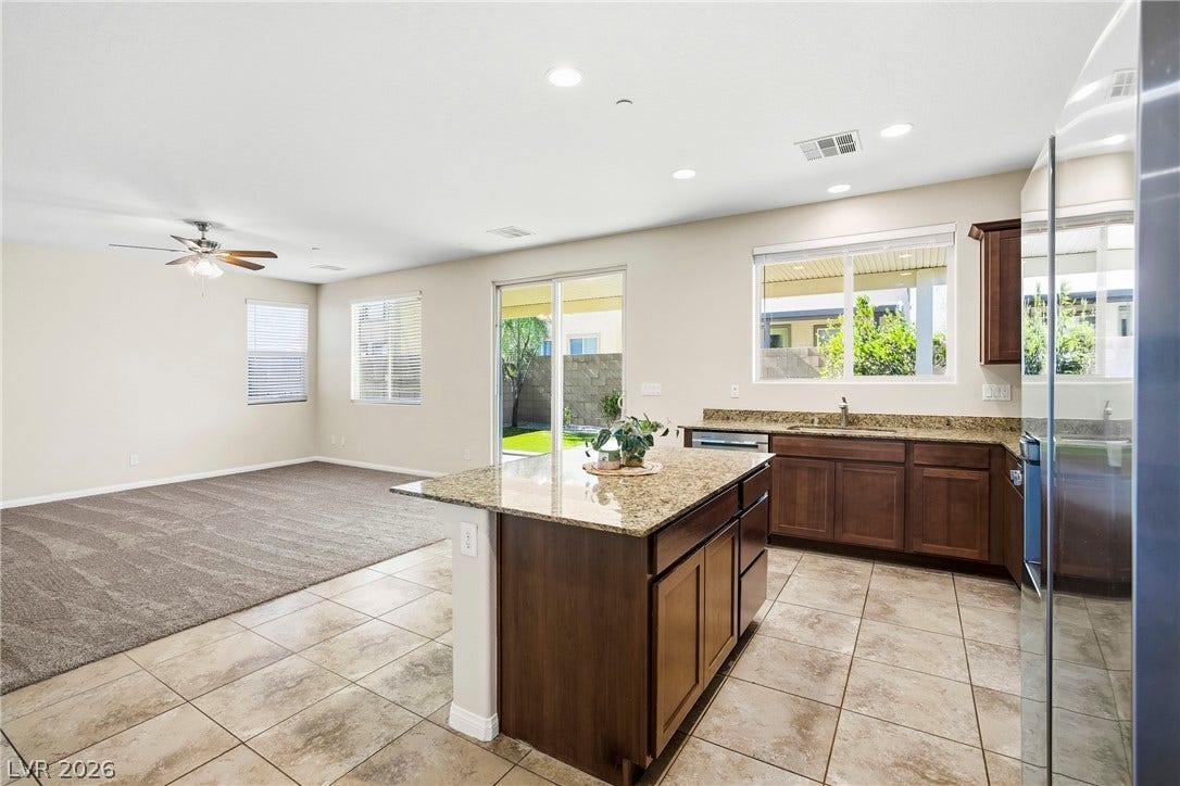 2221 Mundare Drive, Henderson, NV 89002 Granite countertops and tile flooring flow seamlessly into an adjacent carpeted living area.
