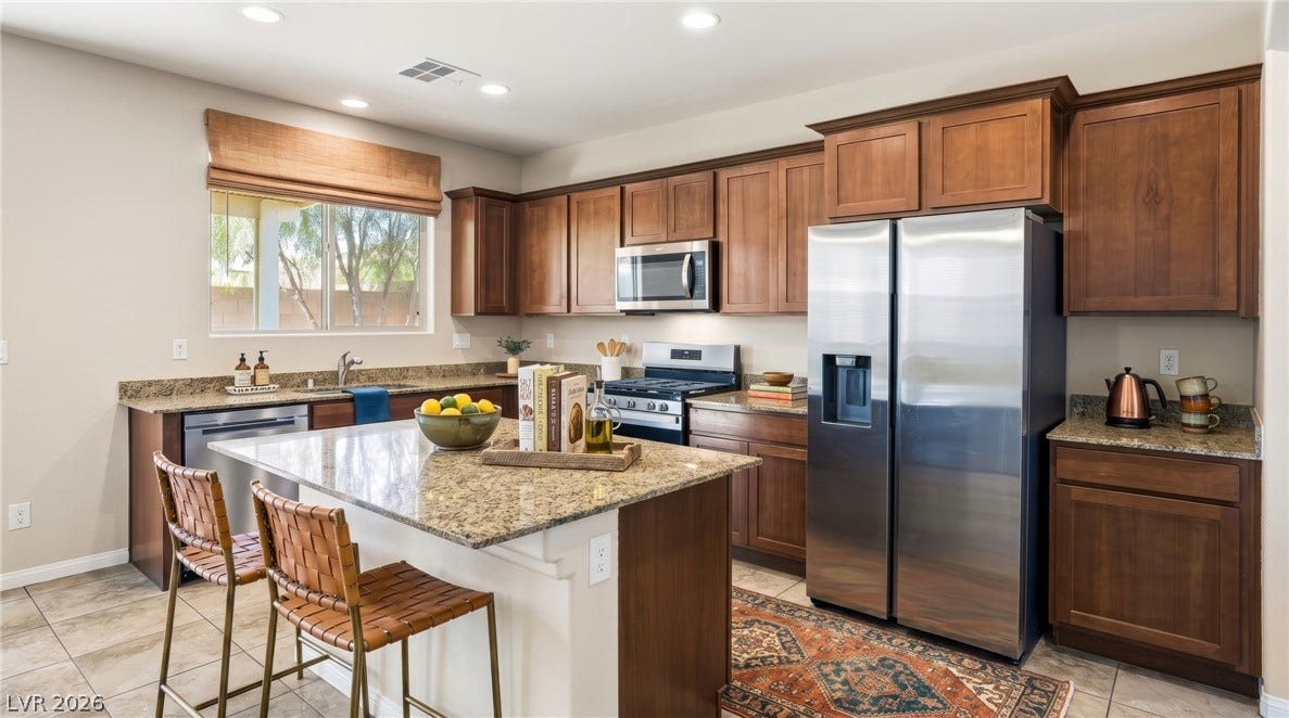 2221 Mundare Drive, Henderson, NV 89002 Rich wood cabinetry and granite countertops frame a spacious central island with tile flooring.