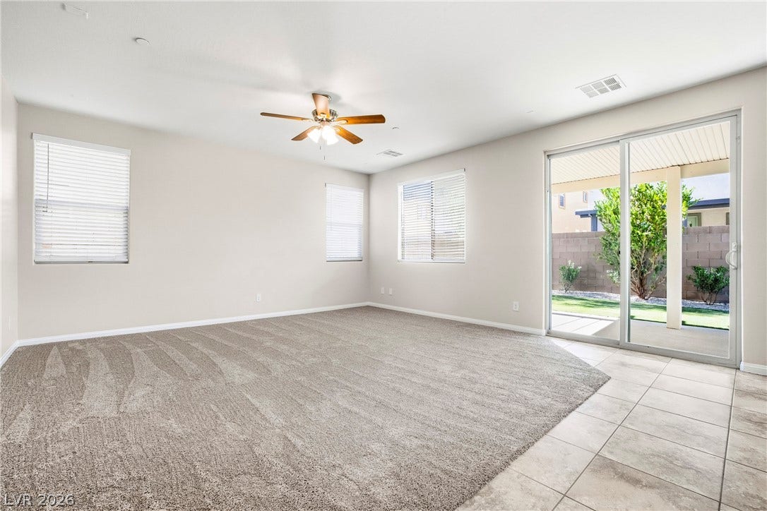 2221 Mundare Drive, Henderson, NV 89002 A spacious living area combines plush carpeting with tile flooring near sliding glass doors.
