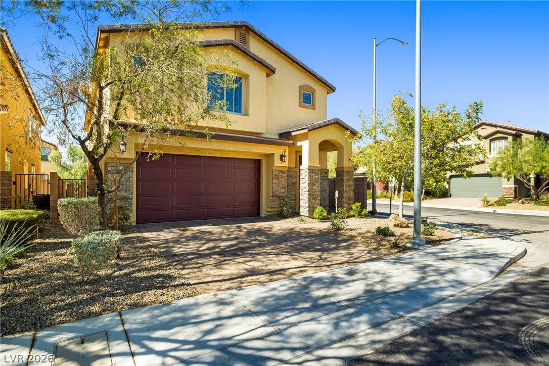 2221 Mundare Drive, Henderson, NV 89002 Elegantly crafted exterior displays rich stone accents and a paved driveway under blue skies.