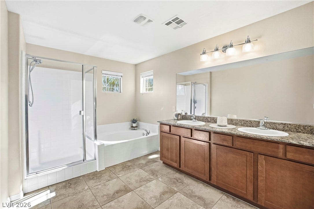 2221 Mundare Drive, Henderson, NV 89002 A spacious layout showcases a double vanity alongside a soaking tub and glass-enclosed shower.