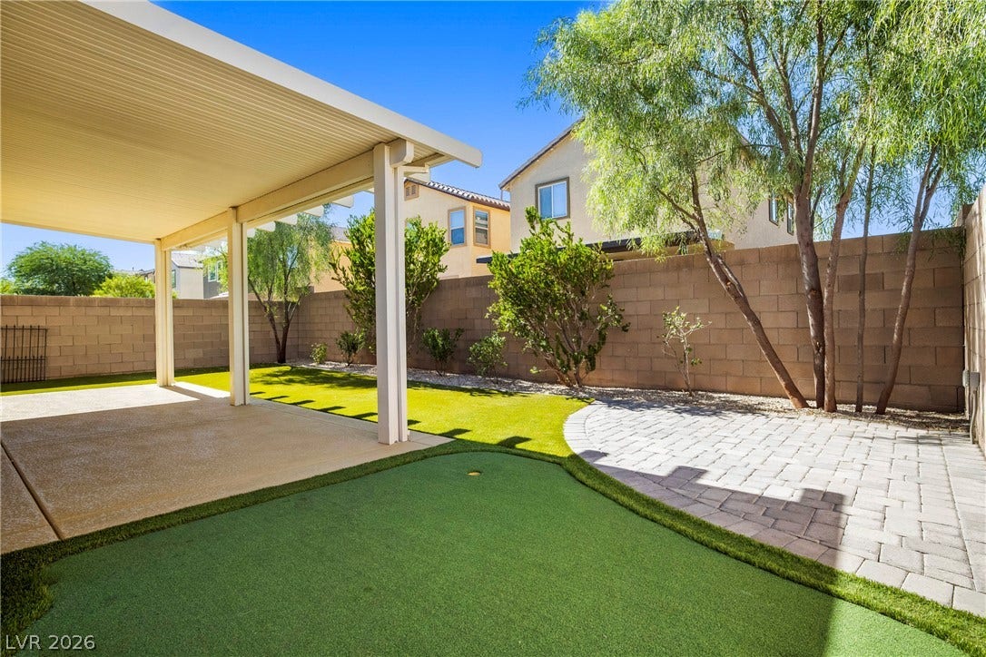 2221 Mundare Drive, Henderson, NV 89002 An inviting covered patio opens to a private backyard with pavers and artificial turf.