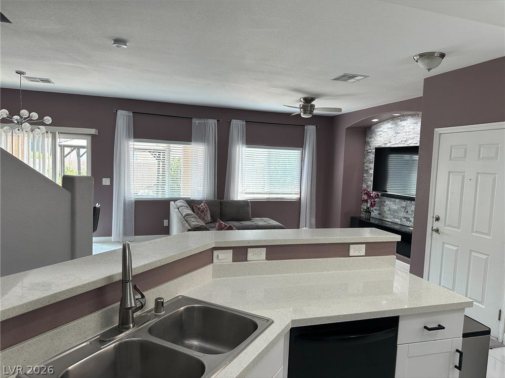 6089 Mustang Breeze Trail, #102, Henderson, NV 89011 Gleaming stone counters look out over an open floorplan complete with a tiled fireplace alcove.