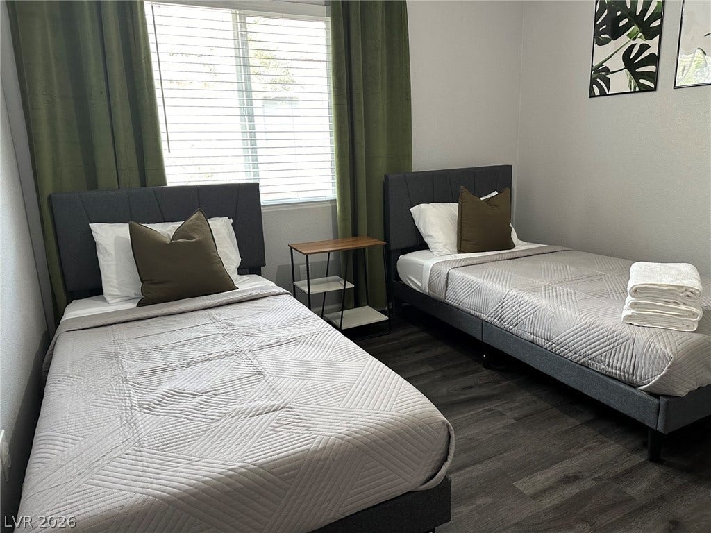 6089 Mustang Breeze Trail, #102, Henderson, NV 89011 A spacious bedroom features dark wood flooring and a large window providing ample natural light.