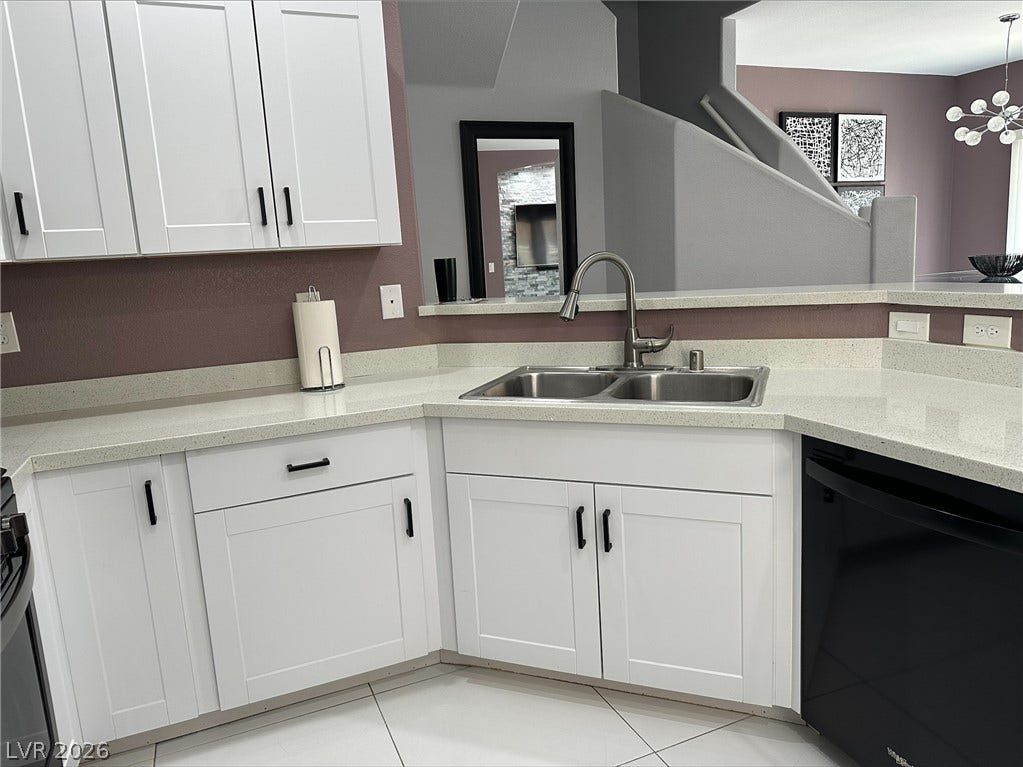 6089 Mustang Breeze Trail, #102, Henderson, NV 89011 White shaker cabinetry and quartz countertops frame a modern sink setup overlooking the main living areas.
