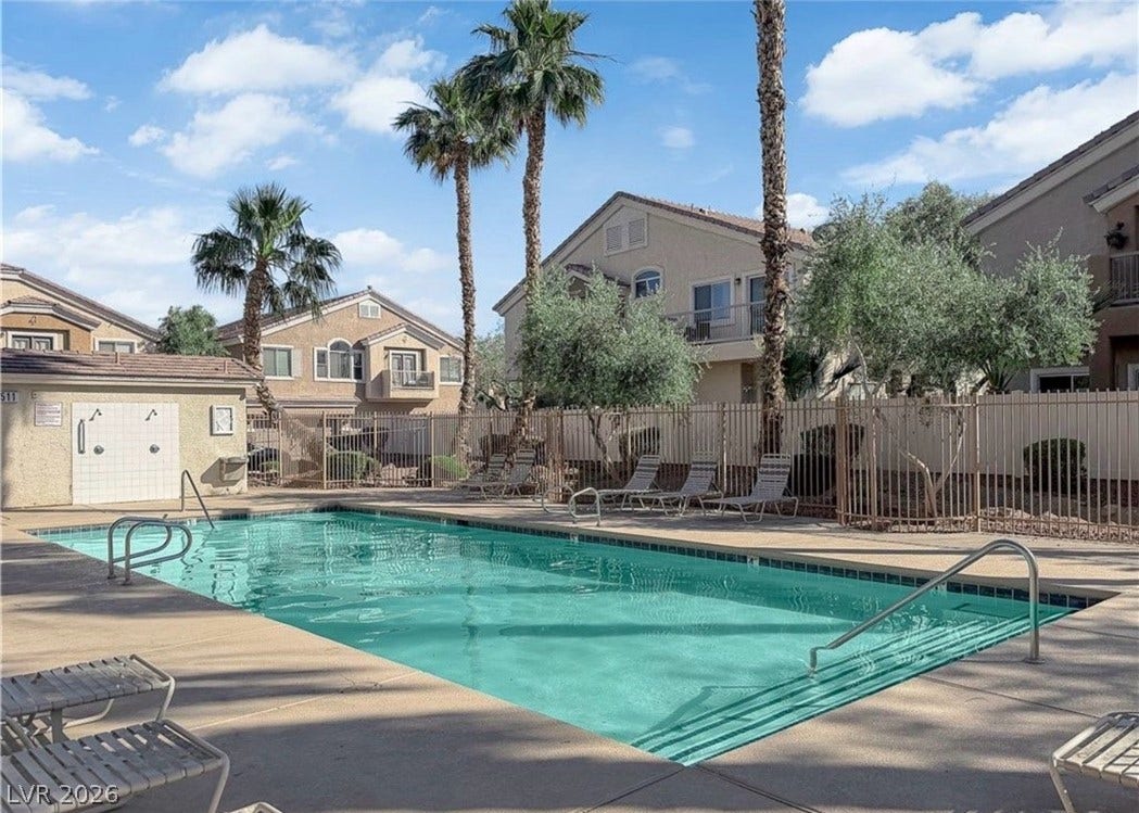 6089 Mustang Breeze Trail, #102, Henderson, NV 89011 A sparkling community pool is surrounded by palm trees and concrete lounging space.