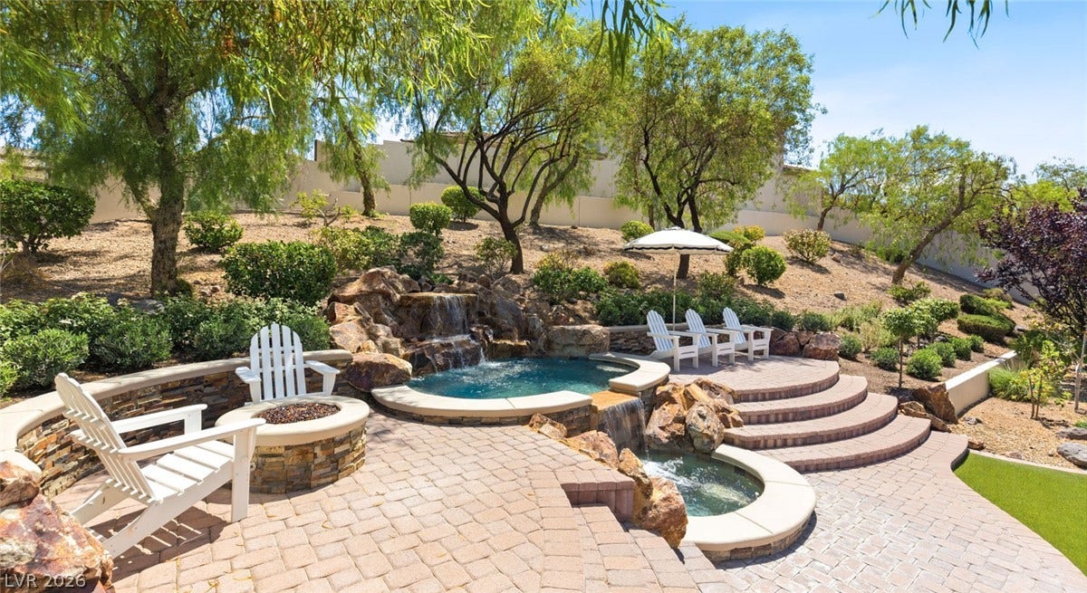 8 Pine Hollow Drive, Henderson, NV 89052 A stone-paved patio surrounds a custom two-tiered jacuzzi and built-in fire pit on a terraced hillside.