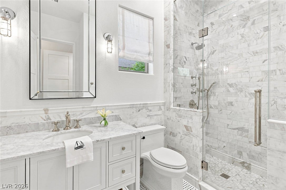 8 Pine Hollow Drive, Henderson, NV 89052 Marble finishes and a glass-enclosed walk-in shower elevate this elegant bathroom space.