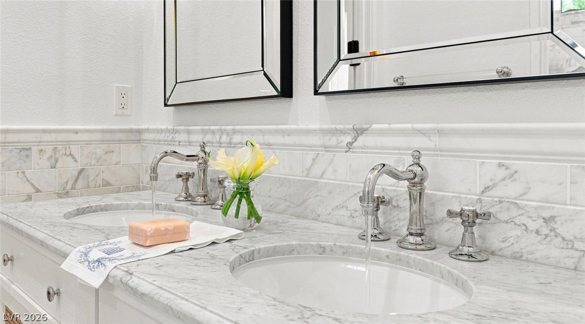 8 Pine Hollow Drive, Henderson, NV 89052 Polished marble countertops and chrome fixtures elevate this elegant double-vanity space.