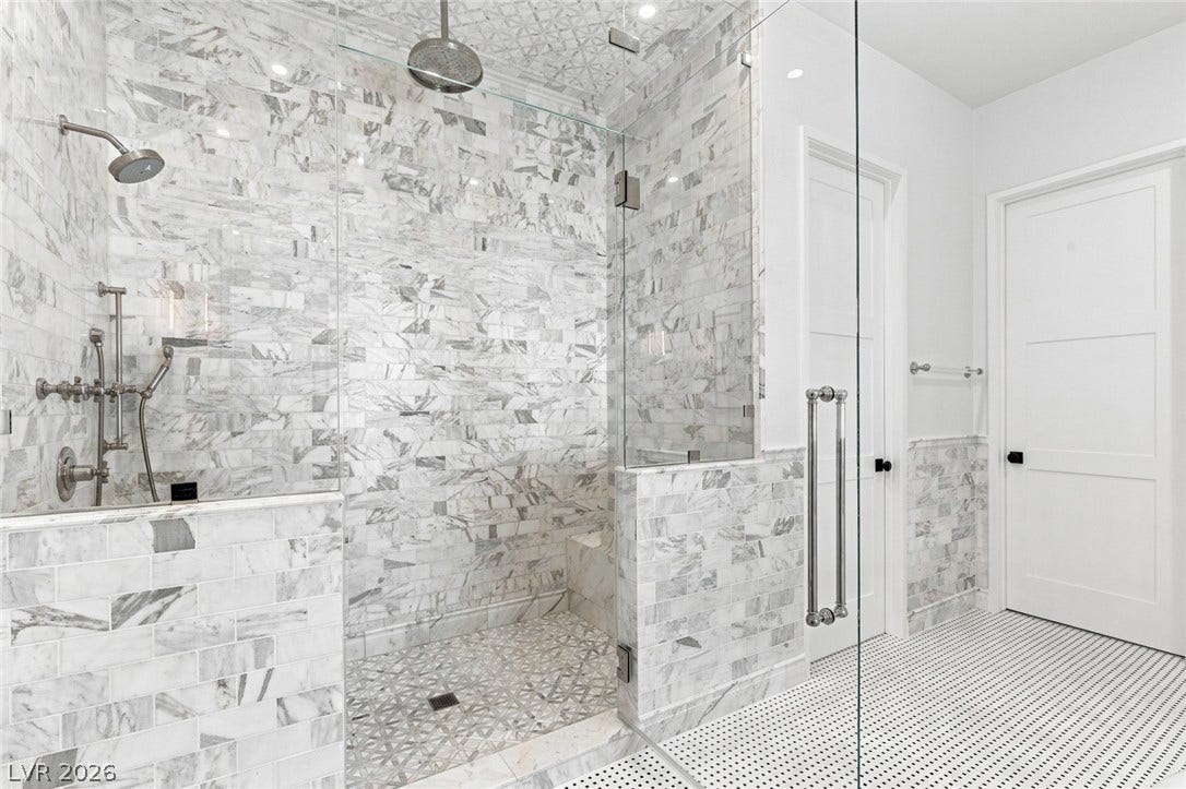 8 Pine Hollow Drive, Henderson, NV 89052 Floor-to-ceiling marble tile elevates this luxurious glass-enclosed shower with custom fixtures.