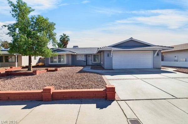 4284 Annie Oakley Drive, Las Vegas, NV 89121 An inviting single-story facade features low brick retaining walls and a spacious concrete driveway.