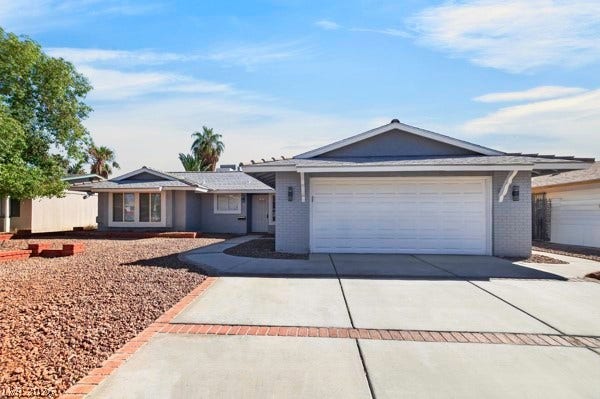 4284 Annie Oakley Drive, Las Vegas, NV 89121 A spacious concrete driveway leads toward the integrated two-car garage of this single-story home.