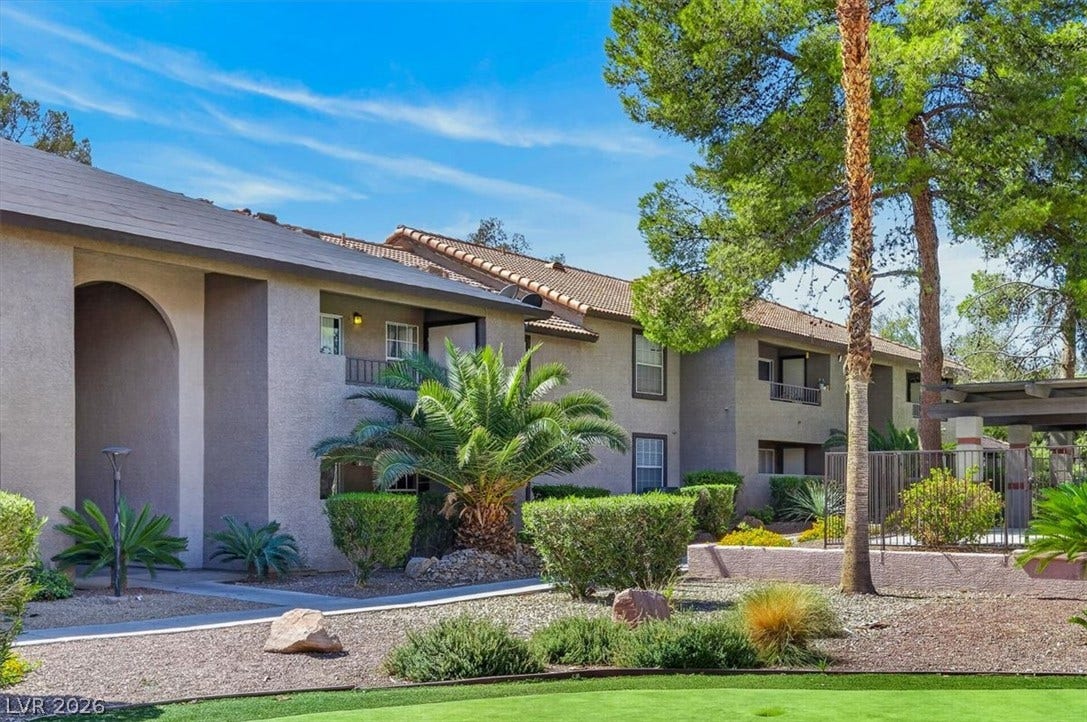 2606 S Durango Drive, #128, Las Vegas, NV 89117 Manicured green lawns and mature shade trees surround the stucco exterior of this residential community.