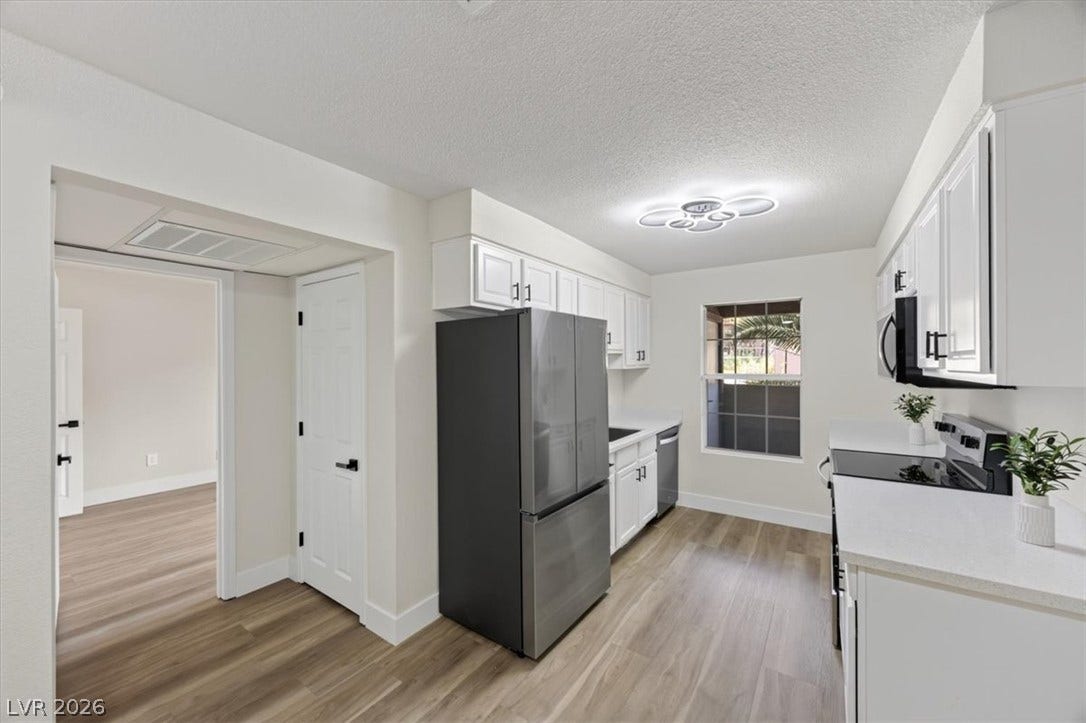 2606 S Durango Drive, #128, Las Vegas, NV 89117 Gleaming stone countertops and wood-look flooring enhance this functional kitchen workspace.