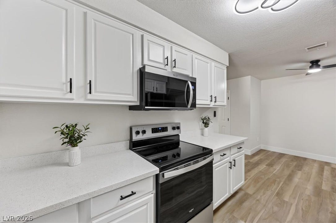 2606 S Durango Drive, #128, Las Vegas, NV 89117 Crisp white cabinetry paired with durable solid-surface countertops runs along modern vinyl plank flooring.