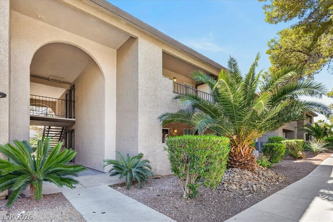 2606 S Durango Drive, #128, Las Vegas, NV 89117 Stucco exteriors and arched entries define this multi-level residential building flanked by palm trees.
