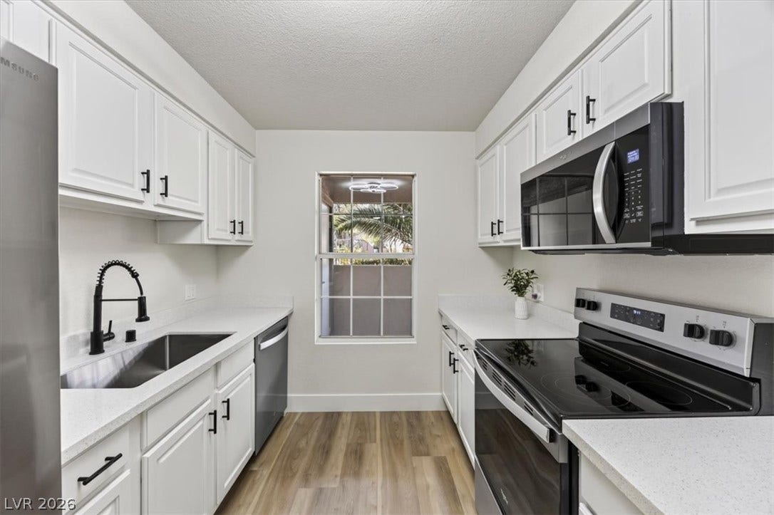 2606 S Durango Drive, #128, Las Vegas, NV 89117 Streamlined galley kitchen features stone countertops alongside stainless steel appliances.