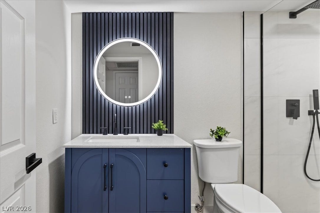 2606 S Durango Drive, #128, Las Vegas, NV 89117 Modern vertical slat accents and sleek stone countertops elevate this contemporary bathroom design.