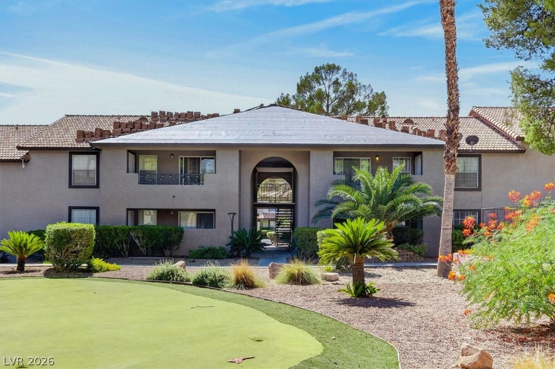 2606 S Durango Drive, #128, Las Vegas, NV 89117 Palm trees and manicured lawns frame the multi-level stucco exterior of this residential community.
