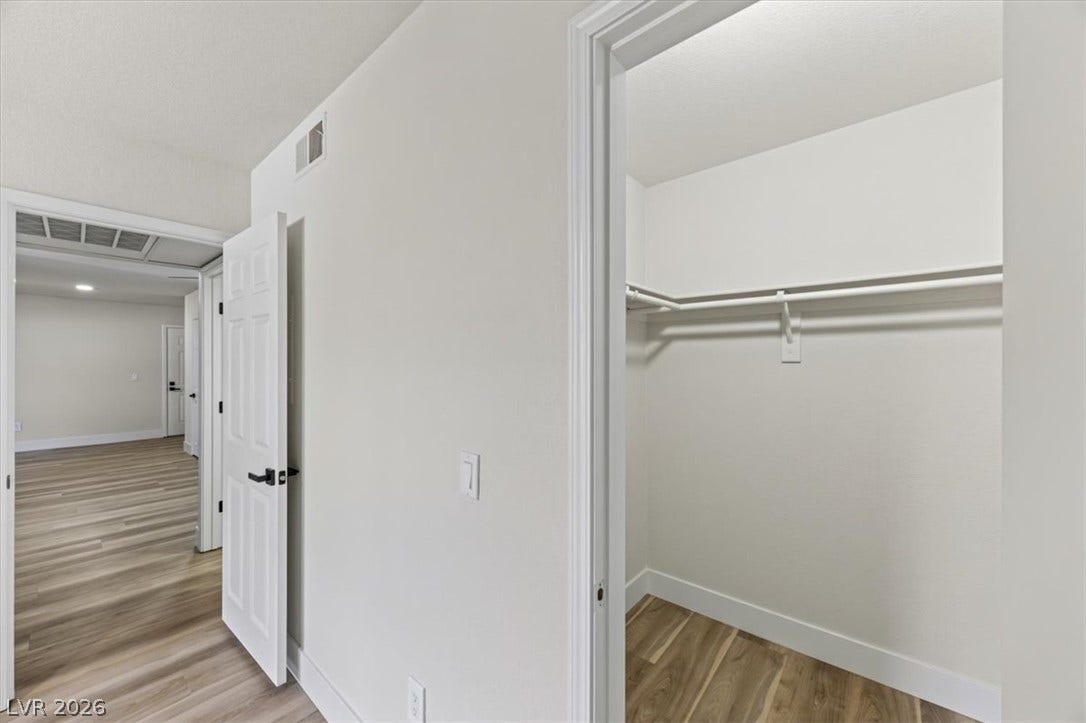 2606 S Durango Drive, #128, Las Vegas, NV 89117 Ample hanging rods and shelving optimize this clean closet space featuring modern plank flooring.