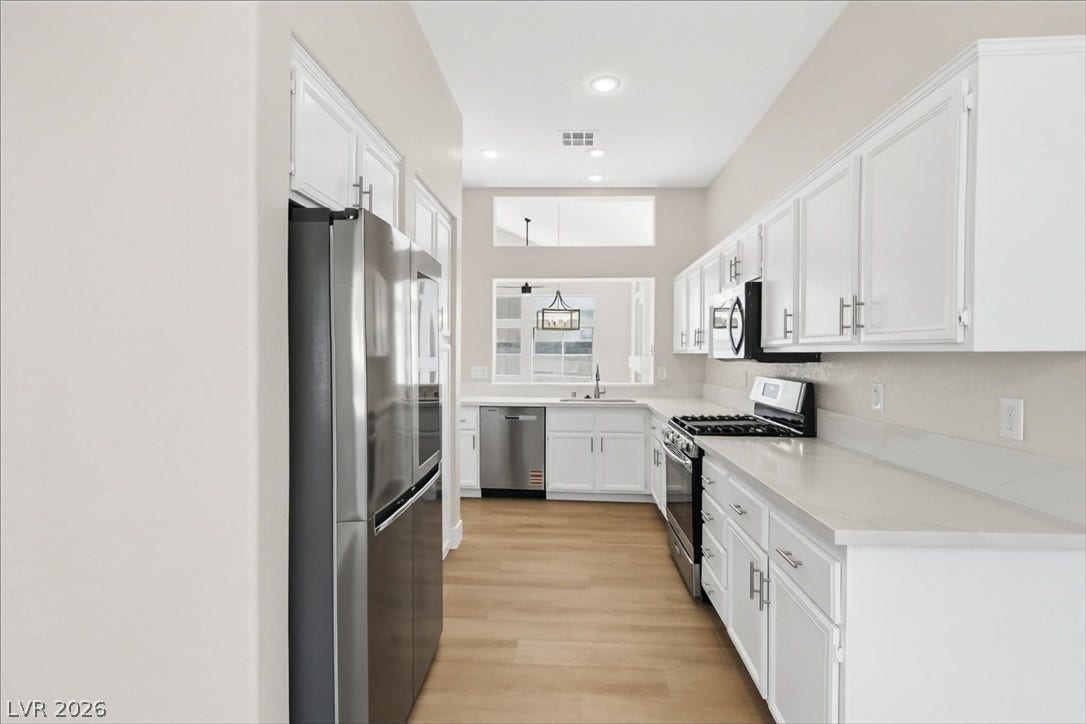 1906 Cardinal Point Street, Henderson, NV 89012 Crisp white cabinetry pairs with sleek countertops and warm flooring in this modern kitchen.