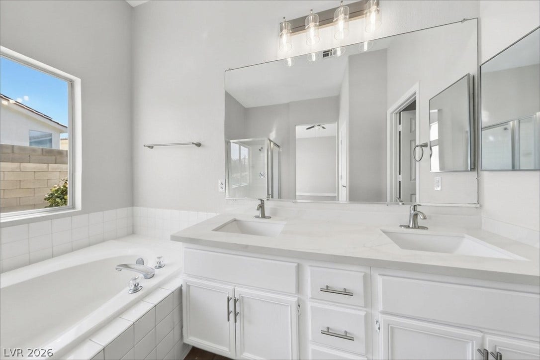 1906 Cardinal Point Street, Henderson, NV 89012 Double vanity sinks and a built-in soaking tub define this bright primary bathroom.