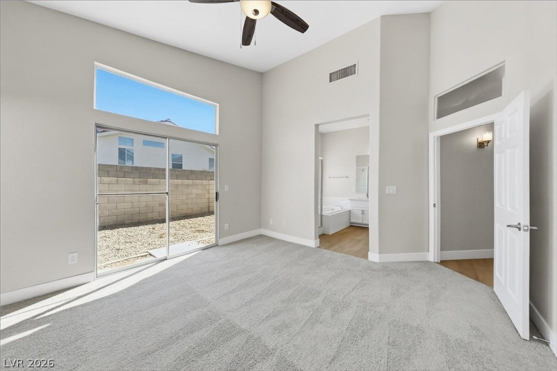 1906 Cardinal Point Street, Henderson, NV 89012 High vaulted ceilings and tall windows elevate this carpeted main suite with sliding door access.