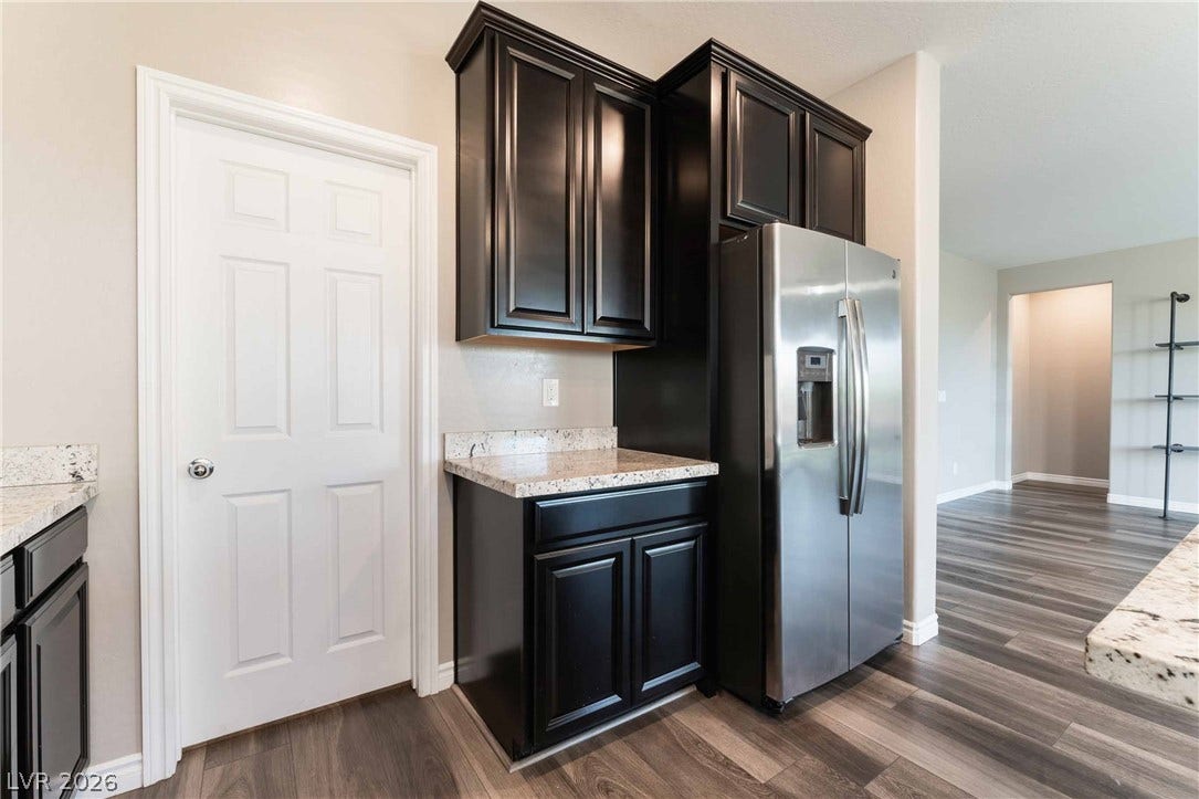1430 Dire Wolf Avenue, North Las Vegas, NV 89084 Rich dark cabinetry and polished stone countertops elevate this modern cooking space.