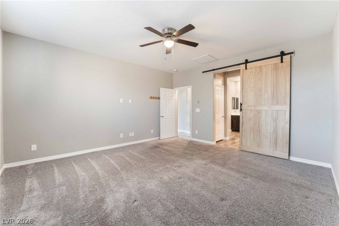 1430 Dire Wolf Avenue, North Las Vegas, NV 89084 Plush carpeting and a rustic sliding barn door enhance this comfortable bedroom suite.