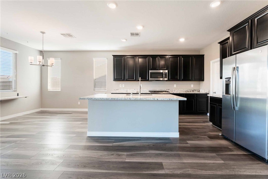 1430 Dire Wolf Avenue, North Las Vegas, NV 89084 Dark cabinetry and a central island highlight this open-concept culinary space with wood-look flooring.