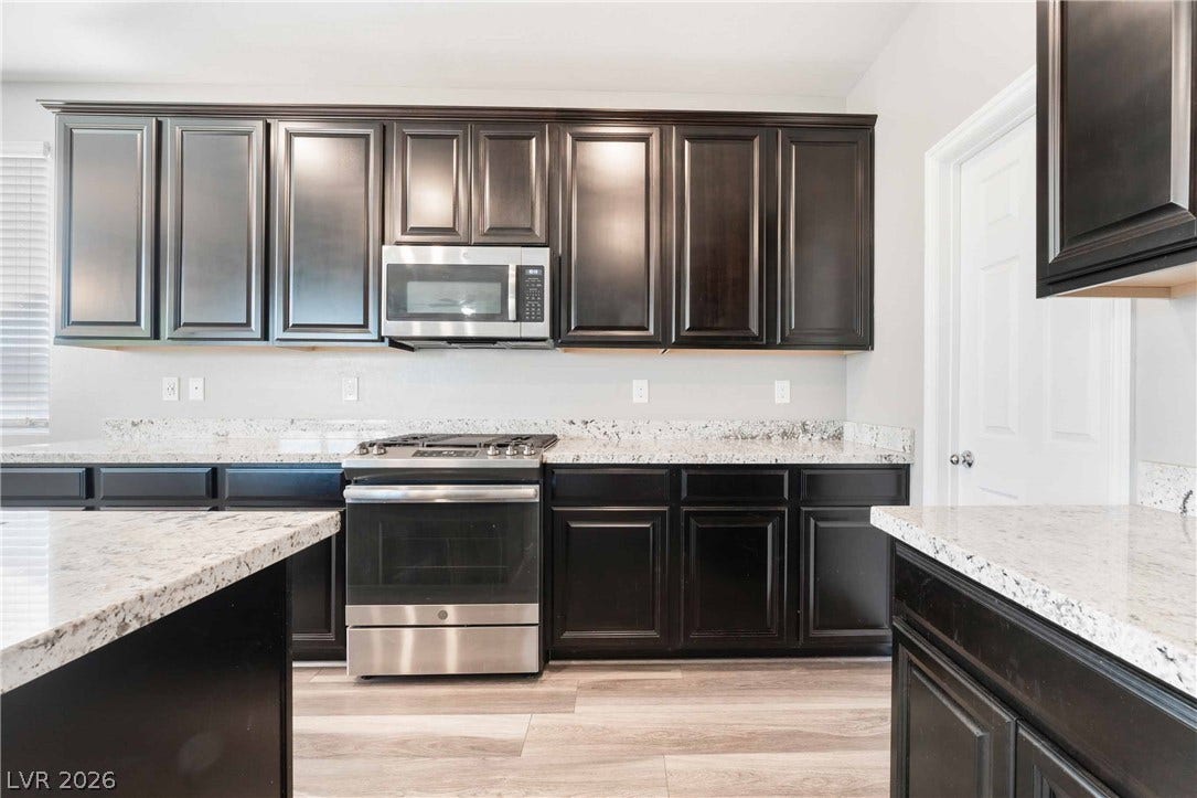 1430 Dire Wolf Avenue, North Las Vegas, NV 89084 Rich dark cabinetry contrasts beautifully with granite countertops in this functional workspace.
