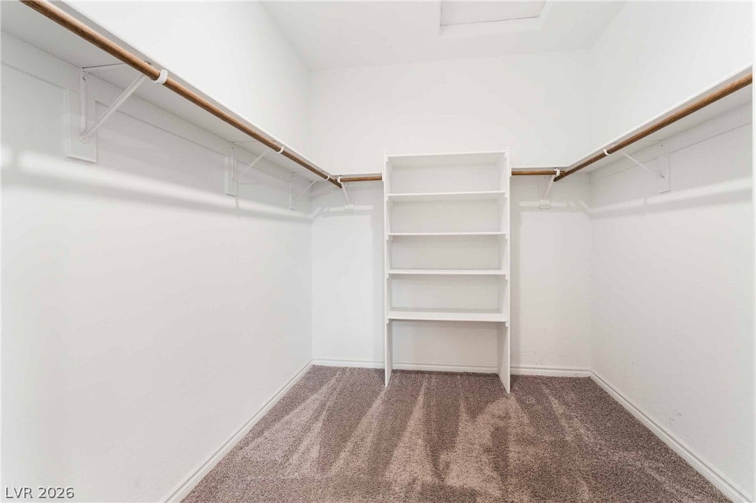 1430 Dire Wolf Avenue, North Las Vegas, NV 89084 Ample storage options define this neat walk-in closet featuring carpet flooring and built-in shelving.