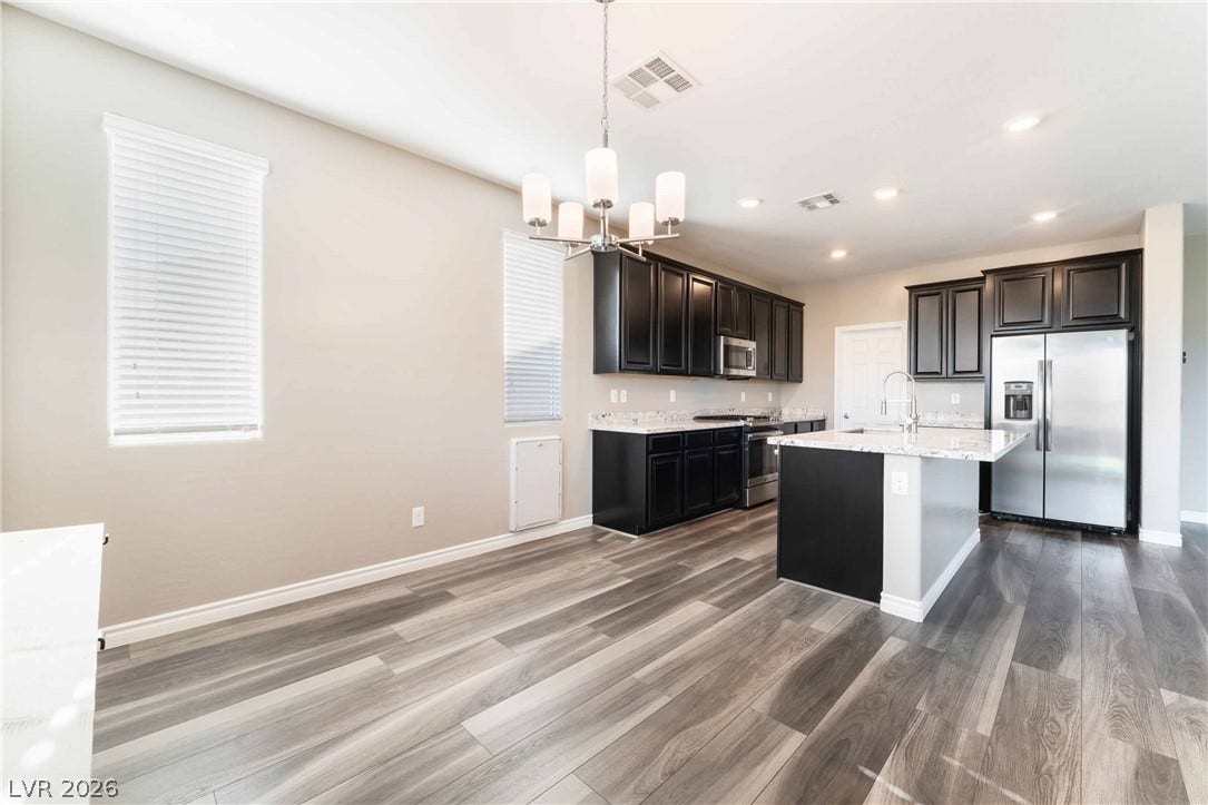 1430 Dire Wolf Avenue, North Las Vegas, NV 89084 Plank flooring runs through an open kitchen area featuring a functional center island.