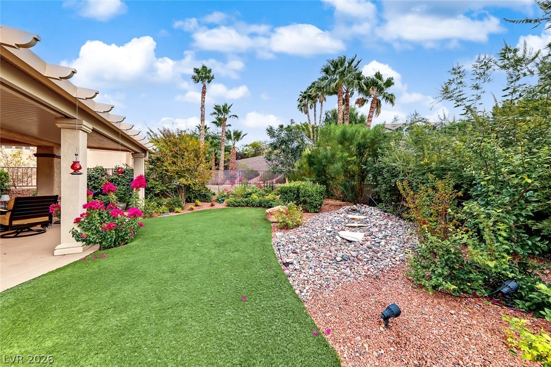 1646 Sebring Hills Drive, Henderson, NV 89052 Lush landscaping and desert stone details create a private backyard retreat under clear skies.