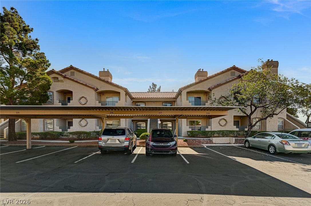 5415 W Harmon Avenue, #1029, Las Vegas, NV 89103 Multi-level residential architecture features designated covered parking and tile roofs against a clear blue sky.