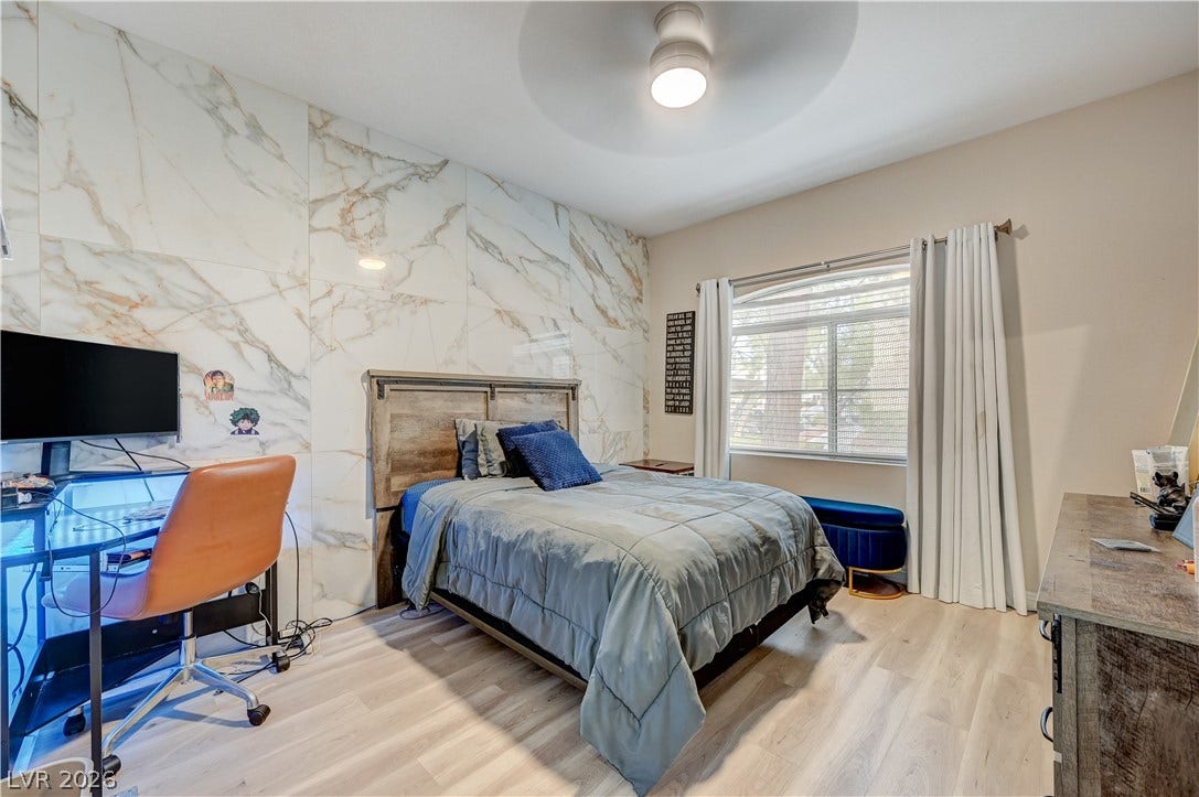 5415 W Harmon Avenue, #1029, Las Vegas, NV 89103 Polished stone-look wall panels and light wood floors elevate this cozy bedroom space.