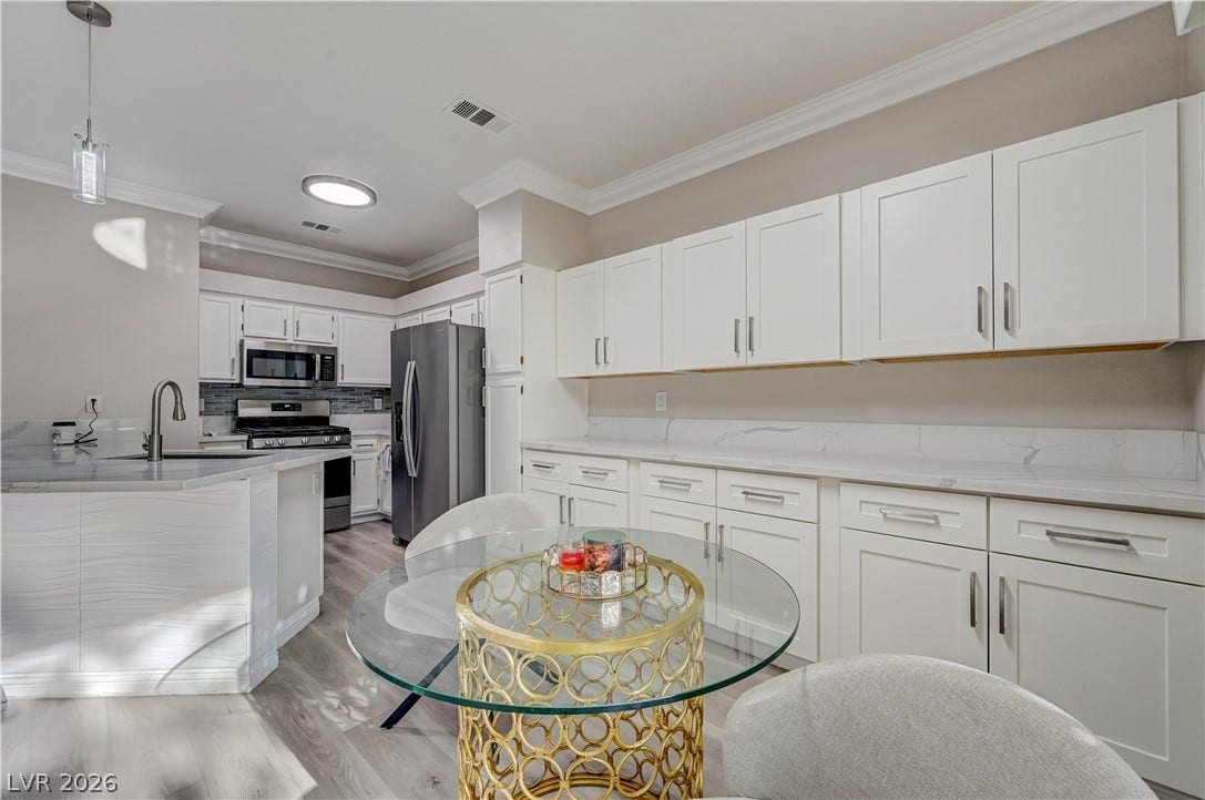5415 W Harmon Avenue, #1029, Las Vegas, NV 89103 Gleaming stone countertops and crisp white cabinetry define this beautifully illuminated modern kitchen space.