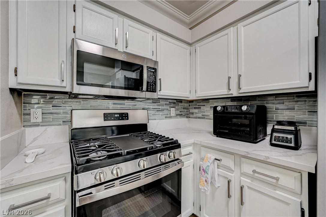 5415 W Harmon Avenue, #1029, Las Vegas, NV 89103 Elegant crown molding complements modern stone countertops and a tiled backsplash.