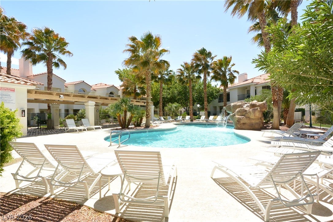 7652 Rolling View Drive, #202, Las Vegas, NV 89149 A sparkling community pool is framed by towering palm trees and stone water feature.