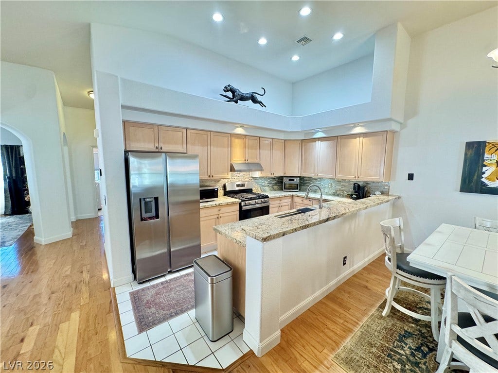 7652 Rolling View Drive, #202, Las Vegas, NV 89149 Gleaming granite countertops and warm wood flooring define this open kitchen under high ceilings.