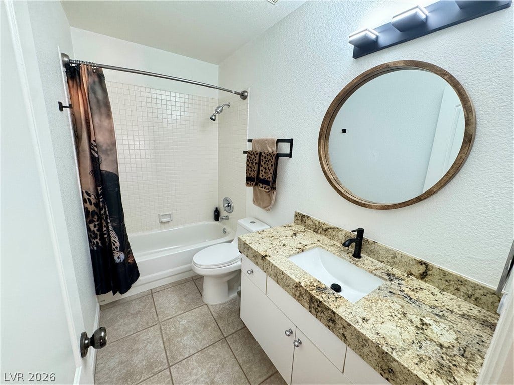 7652 Rolling View Drive, #202, Las Vegas, NV 89149 Natural granite counters and classic tile flooring define this functional bathroom space.