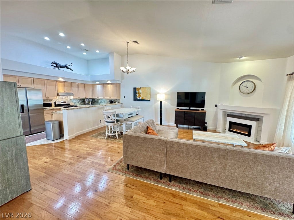 7652 Rolling View Drive, #202, Las Vegas, NV 89149 Warm hardwood floors connect a modern kitchen to an inviting living area with a fireplace.