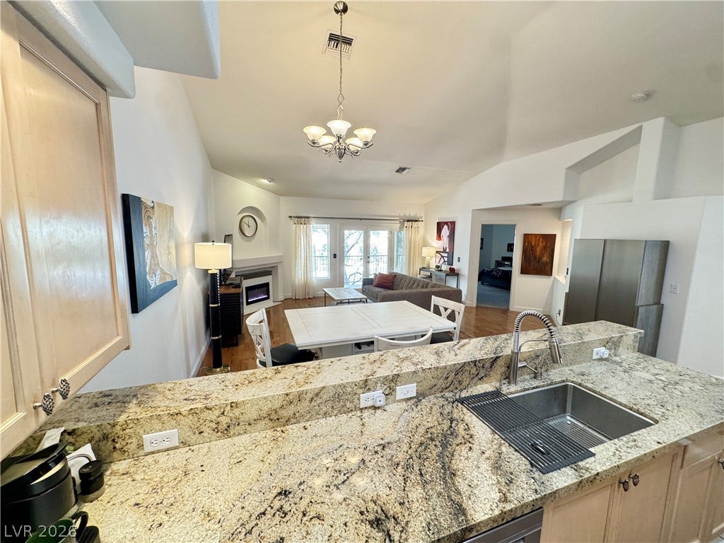 7652 Rolling View Drive, #202, Las Vegas, NV 89149 Gleaming granite countertops overlook a spacious, light-filled living area featuring vaulted ceilings.