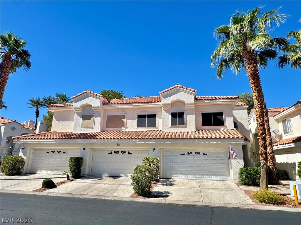 7652 Rolling View Drive, #202, Las Vegas, NV 89149 Spanish tile roofing and towering palm trees frame this multi-car garage townhome exterior.