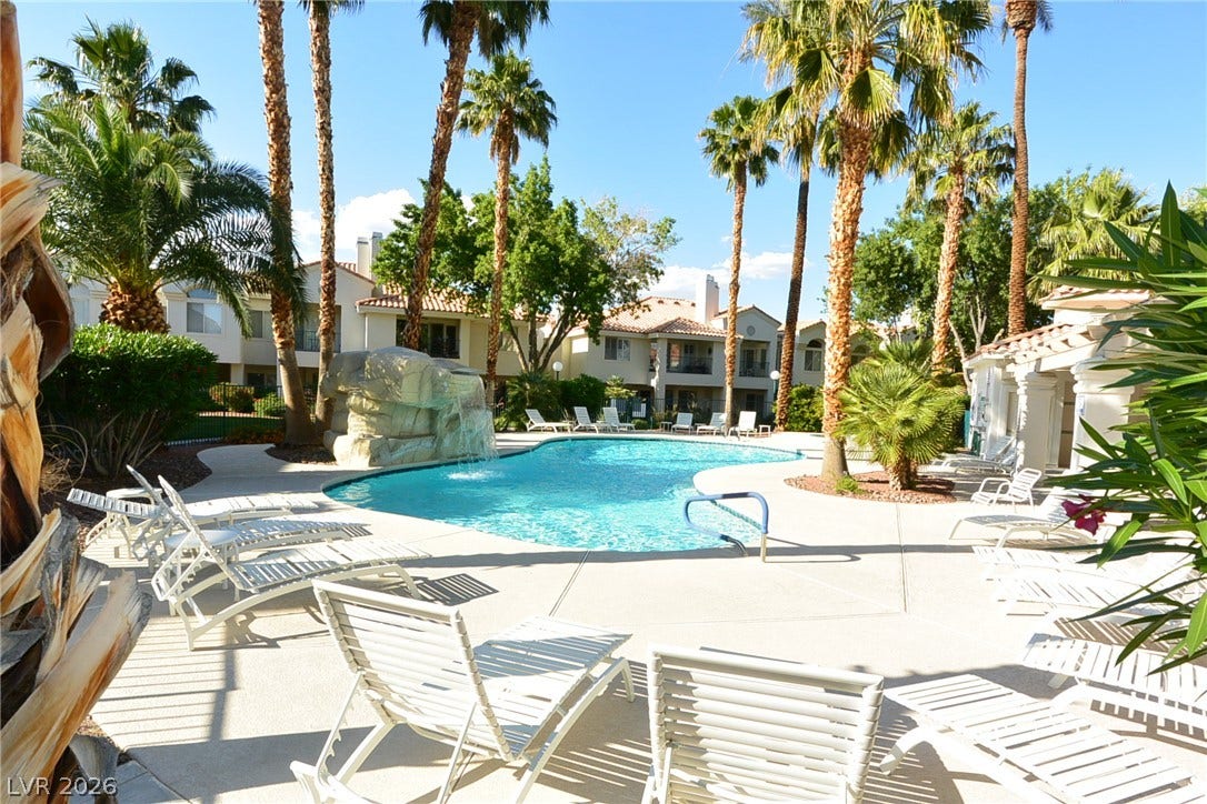7652 Rolling View Drive, #202, Las Vegas, NV 89149 Palm trees surround a refreshing swimming pool featuring a rock waterfall feature.
