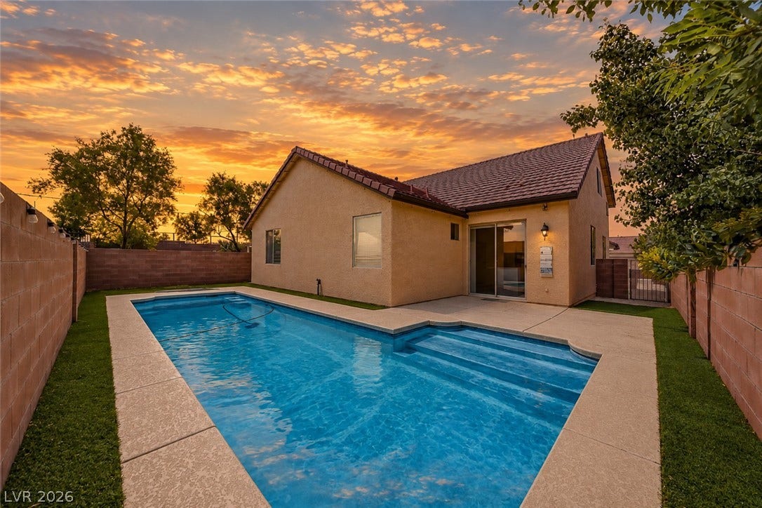 792 Valley Rise Drive, Henderson, NV 89052 An inviting backyard swimming pool rests alongside the stucco exterior under a vibrant sunset sky.