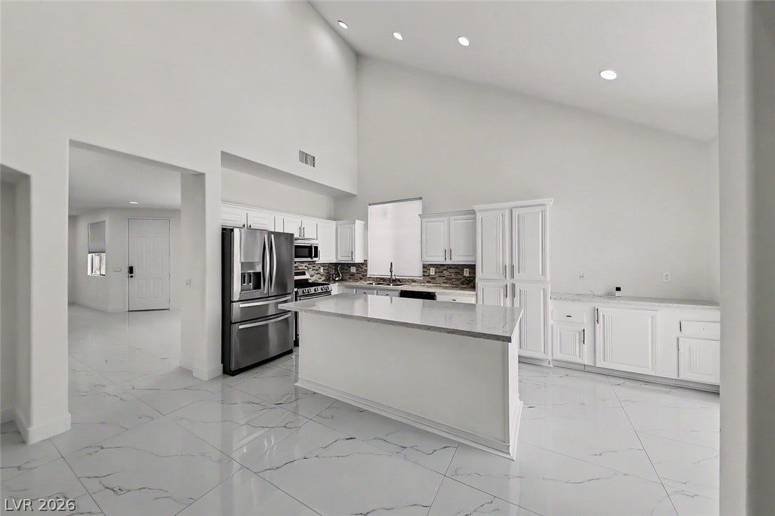 792 Valley Rise Drive, Henderson, NV 89052 Gleaming stone-look tile floors and vaulted ceilings frame this modern kitchen workspace.